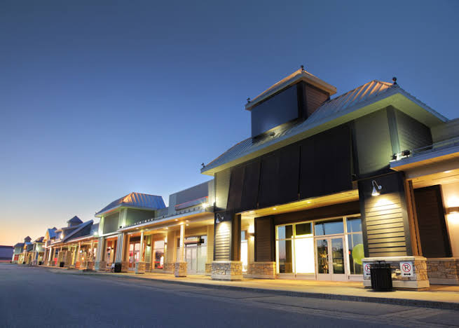 Retail storefronts lit up at dusk